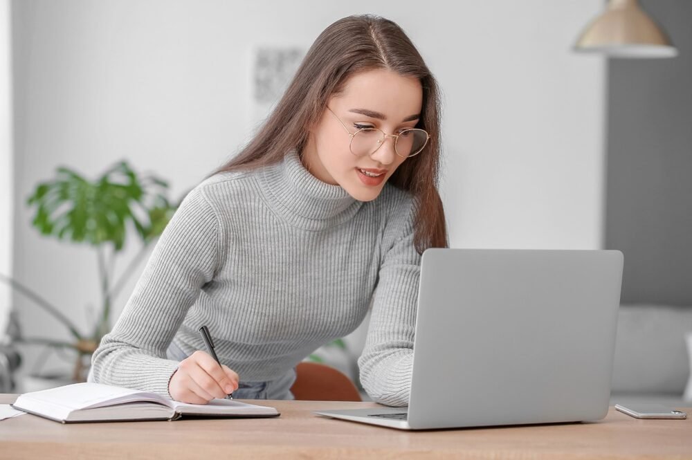 Woman working on a laptop at a desk, planning ways to earn money from her new blog